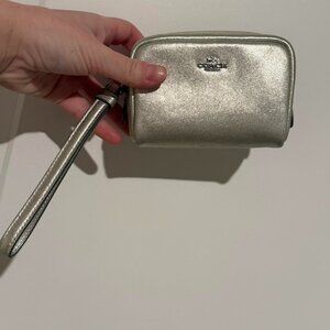 Silver metallic Coach wristlet with zipper closure and wrist strap
